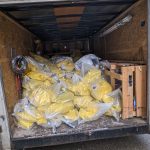 trailer filled with yellow asbestos bags that have been goosenecked with duck tape
