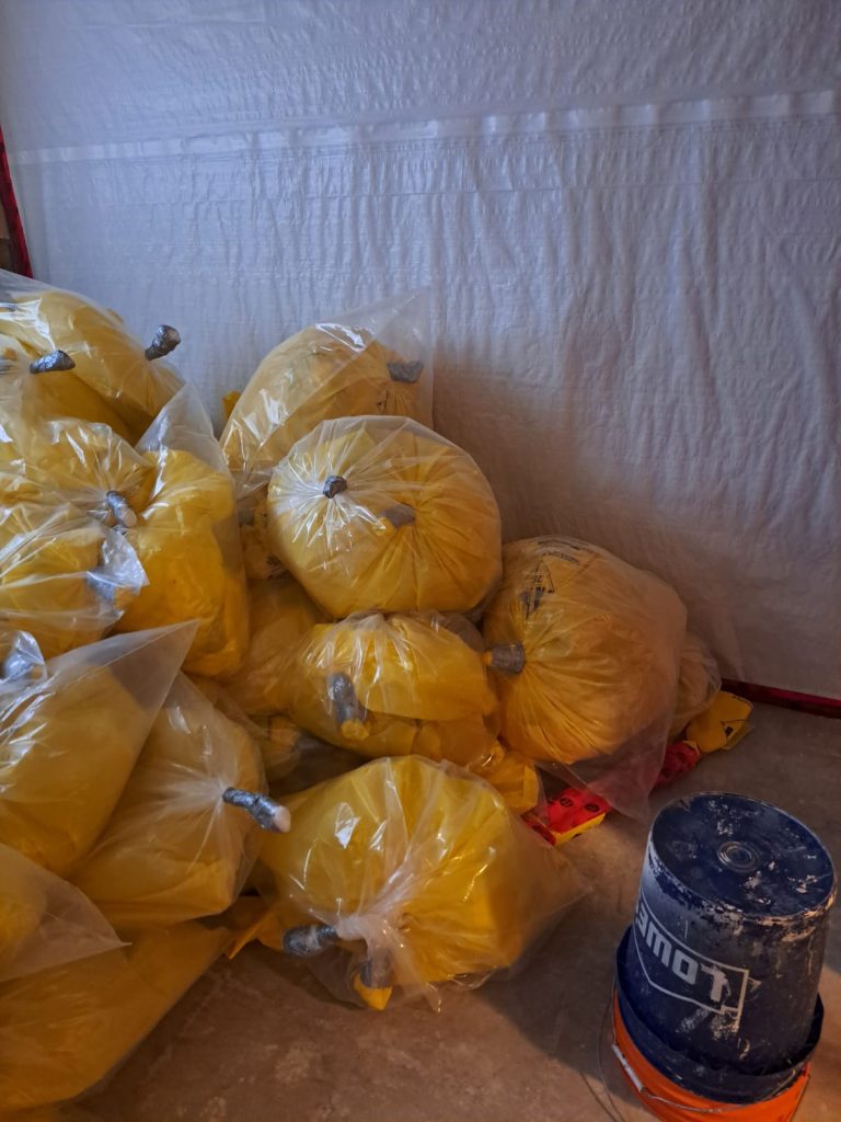 Properly bagged asbestos bags in both yellow and clear bags. They are neatly stacked and gose necked properly.  