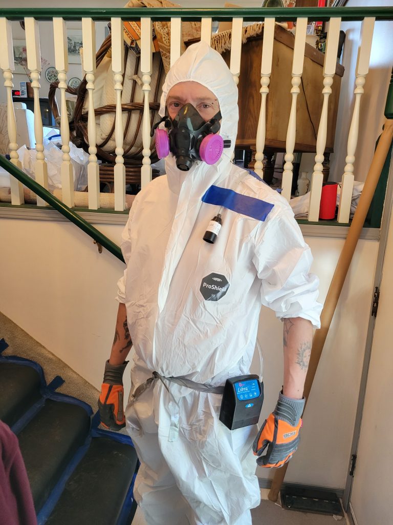 asbestos worker in half mask with P100  and cover alls  and wearing an OCCI air monitoring system 
What Asbestos Workers Wear in the Danger Zone
